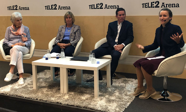 Four panelists with moderator gesturing to audience