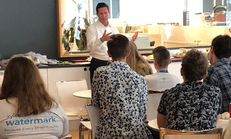 Man addresses a group of young people sitting down