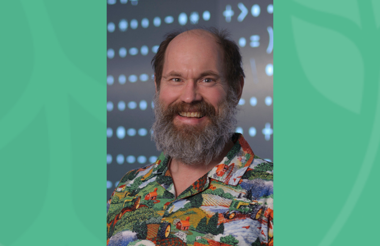 Headshot of Alex Slocum smiling wearing a colorful button down shirt