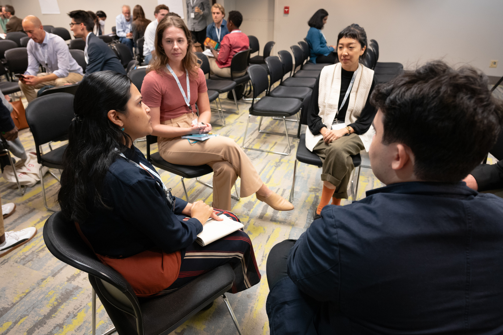 Mrin participating in a discussion with four others in a conference setting. 