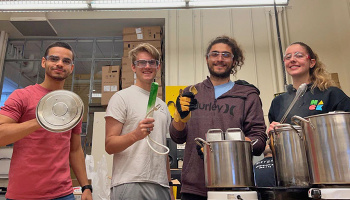 Department of Mechanical Engineering: Katana Finlason, Aly Kombargi, Will Reinkensmeyer, and Ahmad Zakka, in the lab with large metal pots and devices used to make their thermal batteries