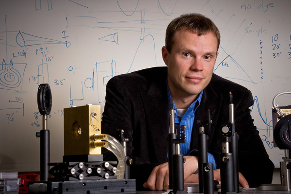 Brad Olsen sitting at a desk with lab equipment 