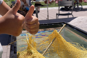 A kid giving two thumbs up overtop a water tank with a net. 