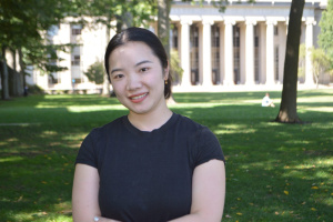 Meng Li photographed outside in front of a lawn and white building