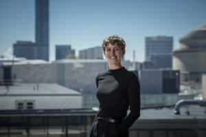 A woman wearing a black shirt standing in front of a city skyline. 