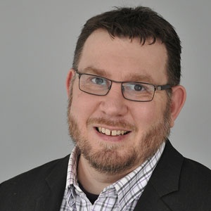 White man with beard and glasses smiling