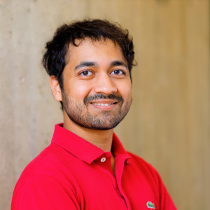 Devashish Gokhale looking at the camera smiling, with dark hair and a red shirt