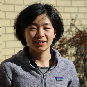 Headshot of Jie Yun in front of a yellow brick building